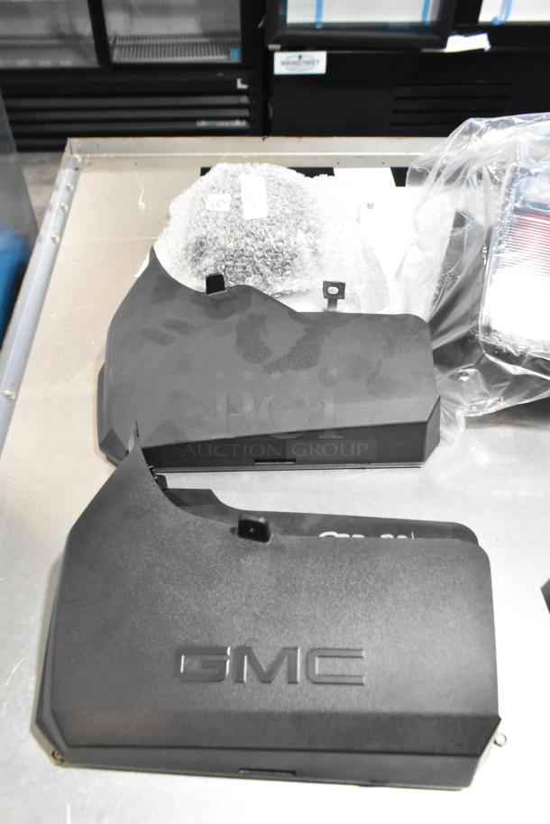Lot of various items in black poly bin, including GMC parts with visible logo. Parts appear new, some bubble wrapped.