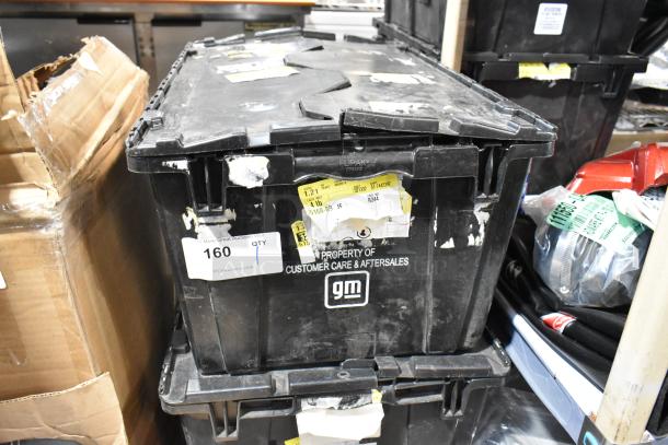 Black poly bin labeled "Property of Customer Care & Aftersales" containing various GMC panels, marked with auction tags.