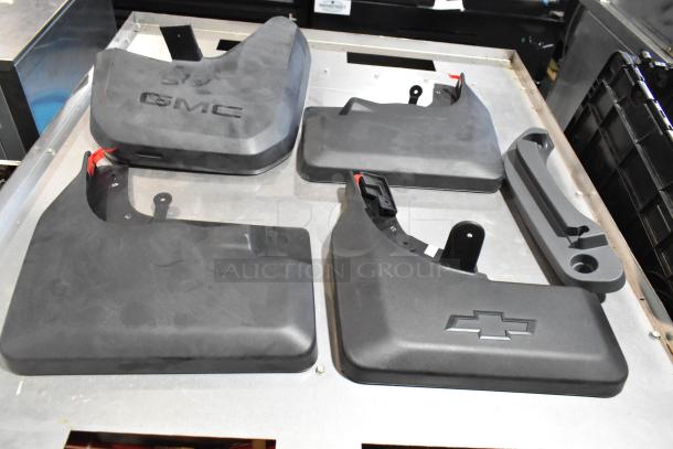 Lot of various automotive panels including GMC and Chevrolet emblems, placed in a black poly bin. Items appear in good condition.