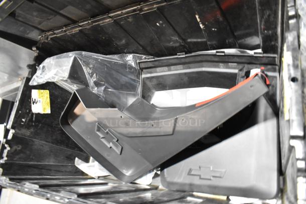 Lot of various items, including GMC panels, in a black poly bin. Panels show Chevy emblem, indicating vehicle type.