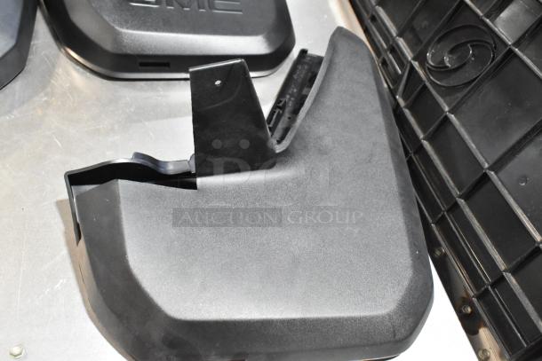 Lot of various black automotive panels in a poly bin. Includes GMC-branded parts. Condition appears used.