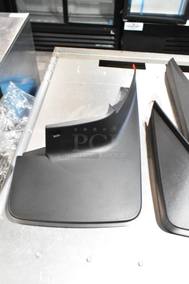 Black GMC panel in good condition, part of a mixed lot in a poly bin, on a metal surface.