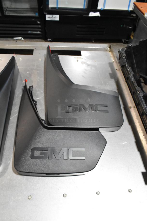 Black GMC panels in poly bin, featuring bold "GMC" logo, part of auction lot with various items. Excellent condition.