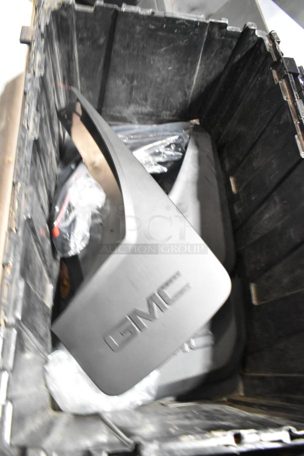 Black poly bin containing various items including GMC panels. Panels are in good condition with "GMC" logo visible.