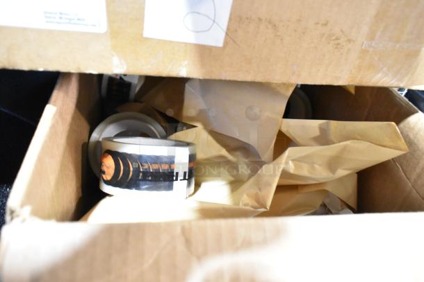 Box containing assorted items, including rolls of tape, partially wrapped. Some labels visible, indicating potential brands.