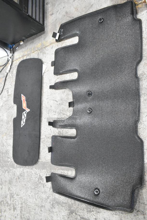Alt text: Car floor mats including textured large mat and black mat with emblem, part of mixed item auction lot.