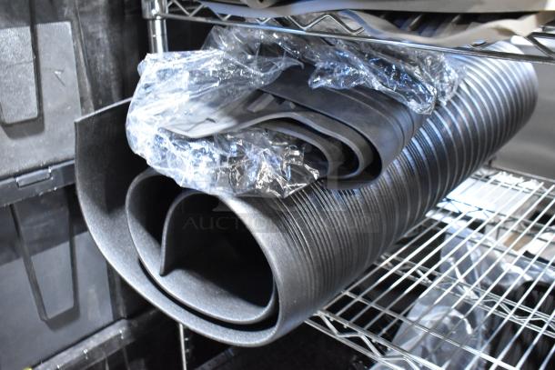 Tiered lot of various items including rolled black car floor mats on a metal shelf, in new condition.