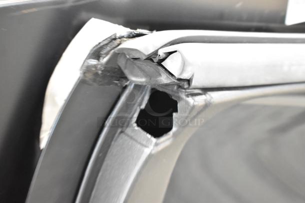 Damaged car panel with visible tear and hole near the edge, highlighting need for repair or replacement. Black material.