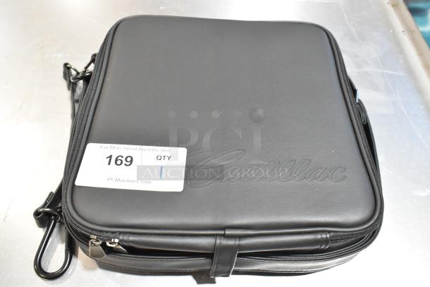 Black Cadillac kit in a sleek case with embossed logo, zipper closure, and tag displaying auction info, item 169.