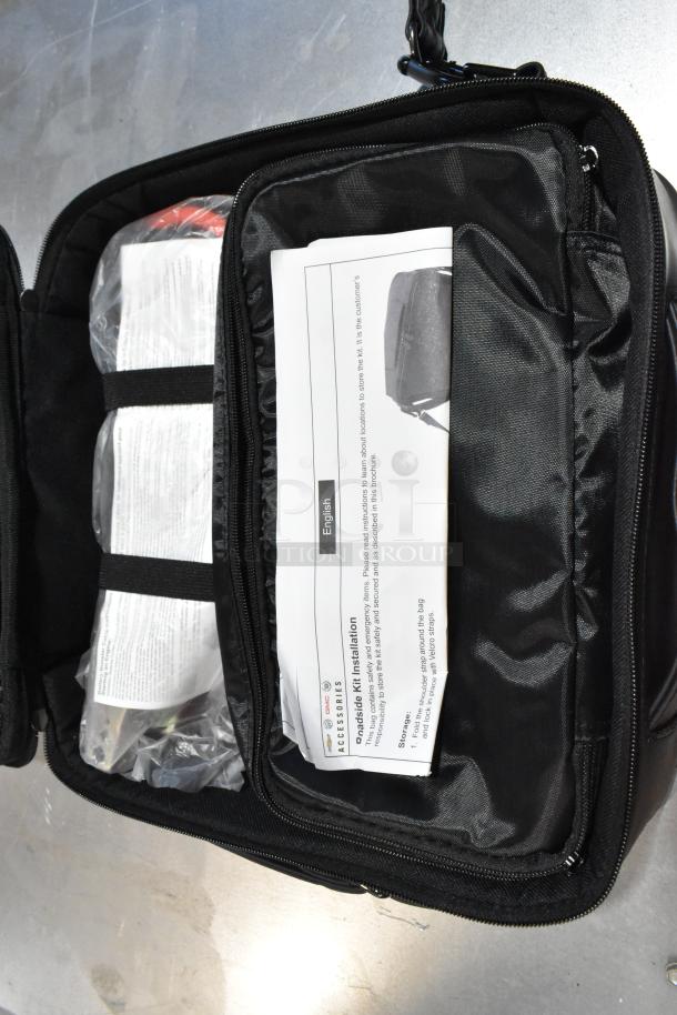 Cadillac roadside kit in black case with zipper, containing instruction manual and plastic-sealed items.