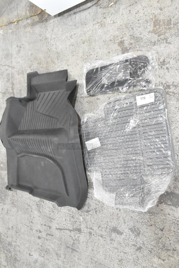 Three assorted items: a textured car floor mat, a wrapped small accessory, and another item covered in plastic, all in new condition.