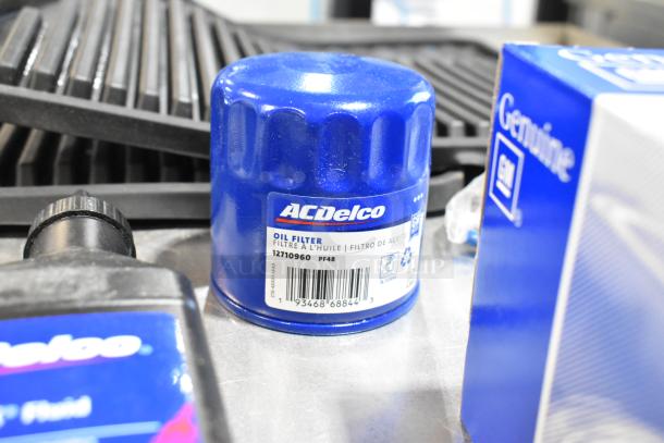 Lot of various items including ACDelco oil filter, Versatrak fluid, and black floor mats in a poly bin.