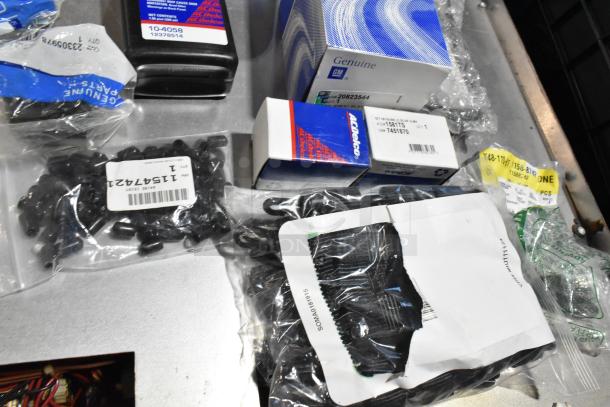 Various automotive items including ACDelco Versatrak fluid and parts in labeled packages, all in a black poly bin.