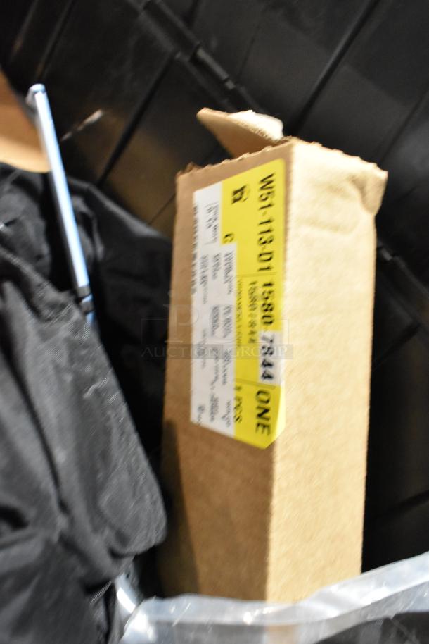 Black poly bin containing ACDelco Versatrak Fluid and floor mats. Visible cardboard box with a yellow label and text.