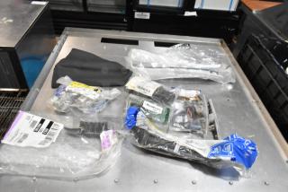 Lot of various items including ACDelco Ultraguard oil fluid, packaged in a black poly bin on a metal surface.