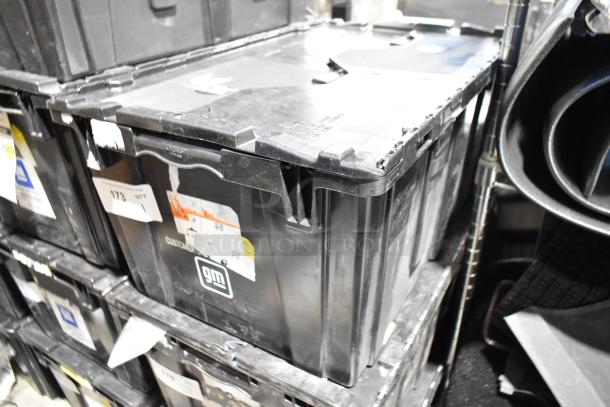 Black poly bin containing a lot of various items, including a cargo net. Labels show "gm" branding and quantity details.
