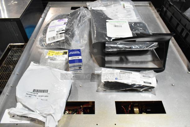 Lot of assorted items in black poly bin, including labeled plastic bags, a Packard contactor box, and various components.