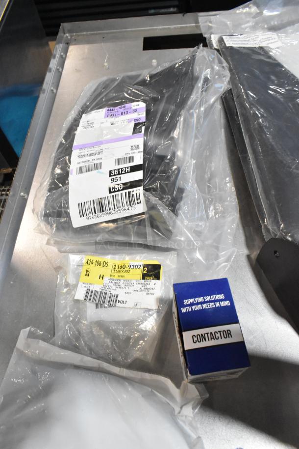 Lot of various items including a cargo net in a black poly bin, featuring labeled packages and a contactor box, in new condition.