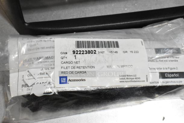 Black poly bin containing various items, including a GM cargo net with label GM# 92223802, made in Mexico, in package.