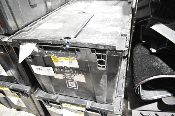 Black poly bin containing various items including mats and an oil filter. Bin shows GM markings and auction labels.