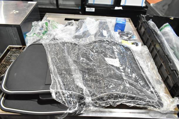 Lot of various items including car mats and oil filter, packed in a black poly bin. Items appear in new condition with packaging.