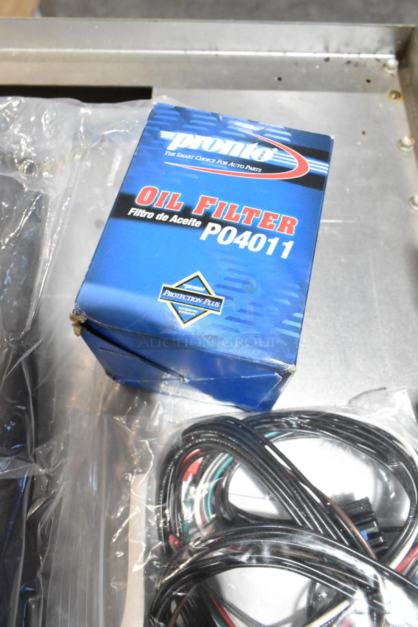 Alt text: "Lot with Pronto oil filter PO4011 box, coiled wires, and mats in a black poly bin."