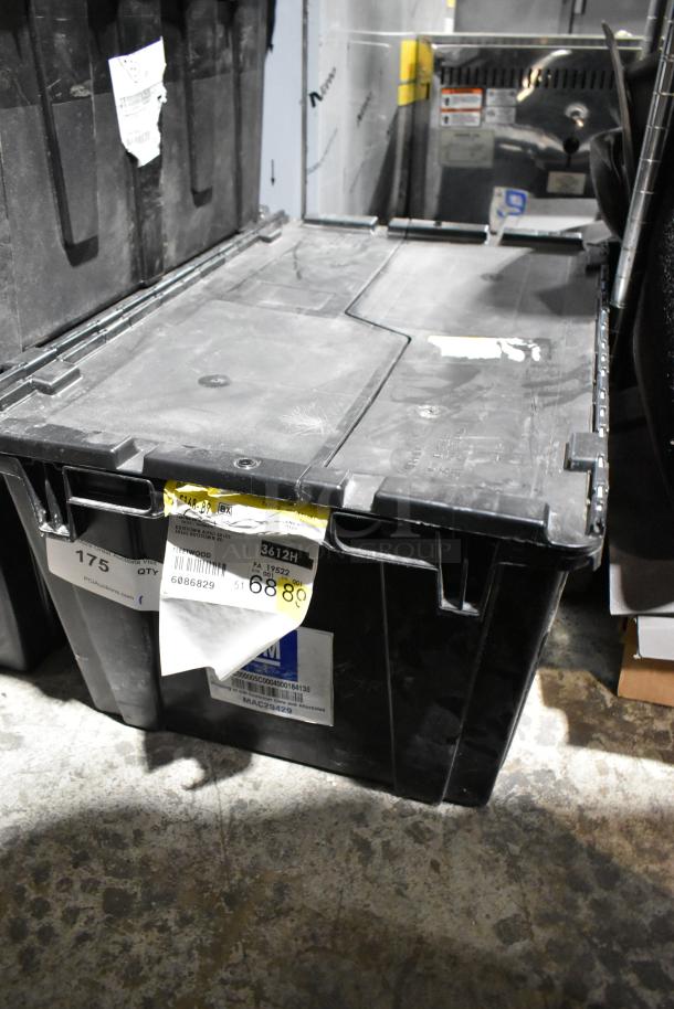 Black poly bin containing assorted items including GM wheel locks and stick shift, visible labels indicating item details.