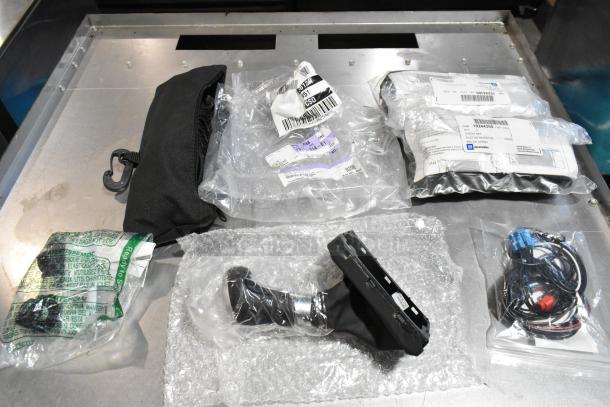 Lot of various items including GM wheel locks and stick shift in a black poly bin, some in original packaging with labels.