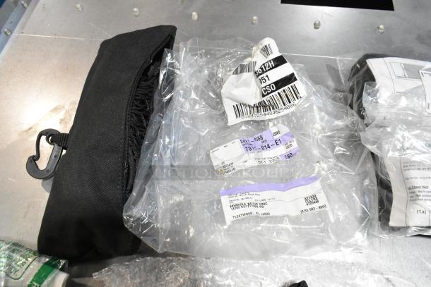 Lot of assorted items in a black poly bin, featuring GM wheel locks and a stick shift. Includes labeled packaging.
