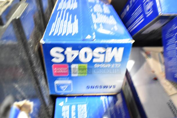 Lot of items with Samsung CLT-C504S/XAA toner cartridge boxes in black poly bin. Bright blue packaging visible.
