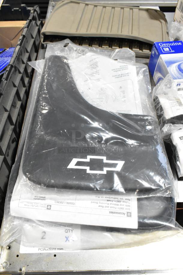 Lot of assorted items in black poly bin, featuring Chevrolet floor mats in protective plastic, with GM Genuine Parts box visible.