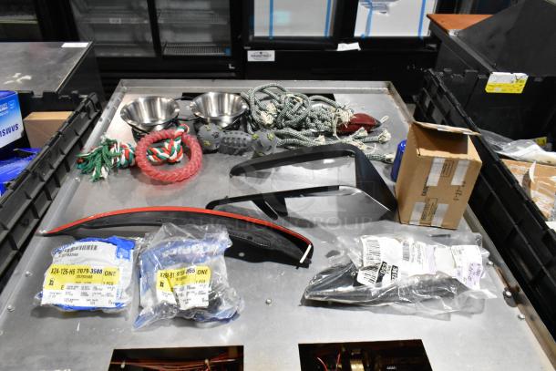 Lot of various items including dog toys in a black poly bin, featuring rope toys, bowls, and sealed items with labels.