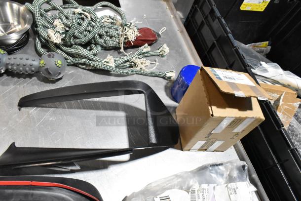 Lot of various items including dog toys, rope, and boxes in a black poly bin. Visible tags and labels on boxes.