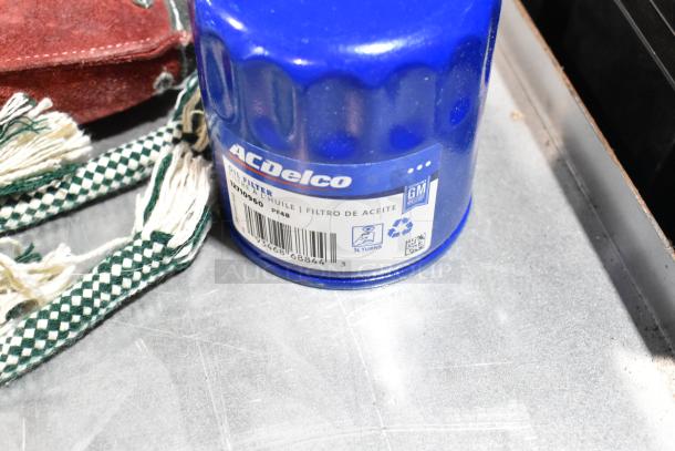 A blue ACDelco oil filter with label details next to a green and white checkered rope toy.