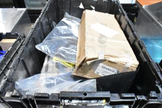 Various items in a black poly bin, including mud flaps labeled 22935639 and a worn cardboard box. Mixed condition.