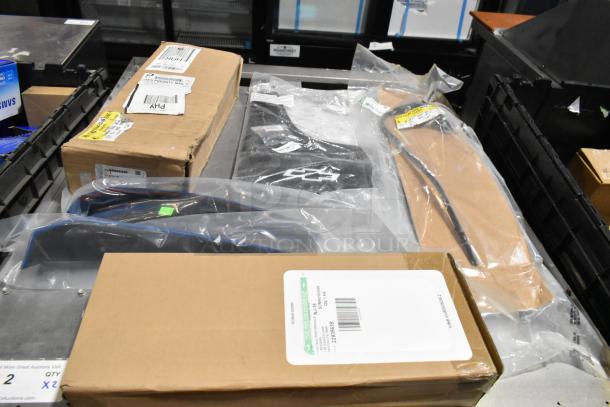 Lot with various items including black mud flaps (22935639) in a poly bin. Includes sealed packages and cardboard boxes.