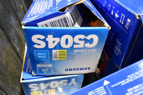 Lot of Samsung C504S ink cartridges in original packaging, stored in a black poly bin. Boxes show minor edge wear.