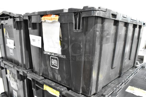Black poly bin containing a lot of various items, including a ZP505 label printer and keyboards, labeled "GM Customer Care & Aftersales."