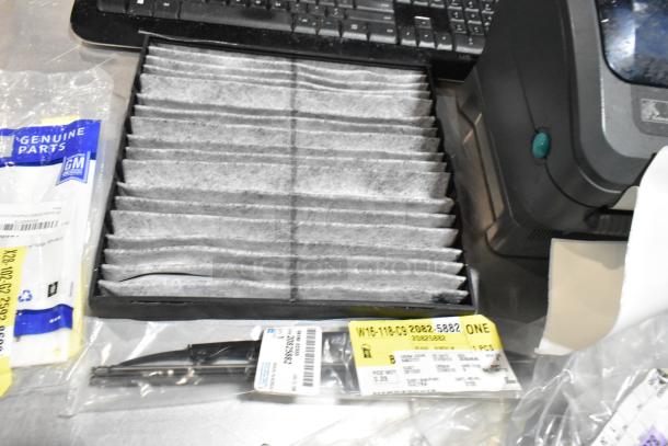 Lot with ZP505 label printer, keyboards, GM parts in a black poly bin. Includes air filter and labels. Good condition.