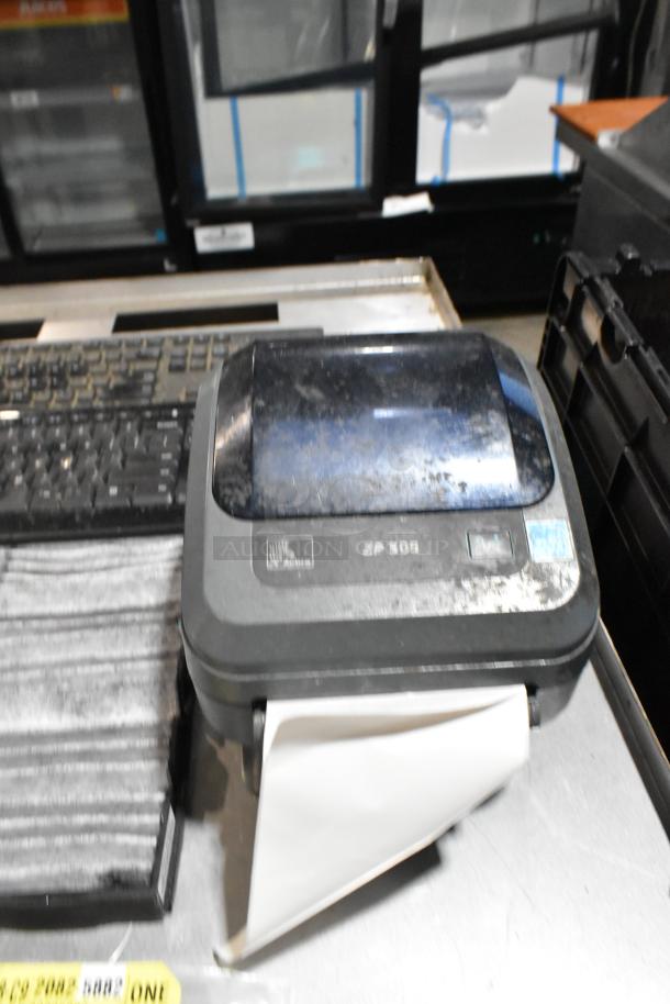 Lot of items in black poly bin; includes ZP505 label printer with visible wear and keyboards.
