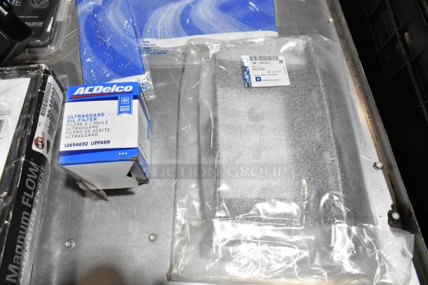Lot of various items including ACDelco Ultragard oil filter, auto license plate frame, and parts in a black poly bin.
