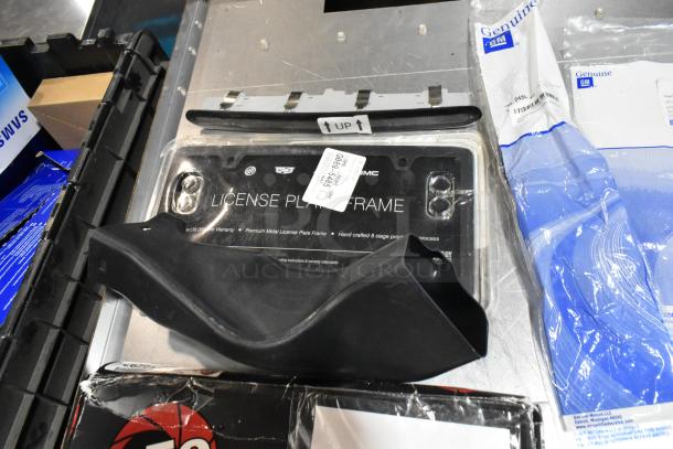 Lot with black poly bin, includes premium metal license plate frame, air filter, and GM genuine parts. Appears unused.