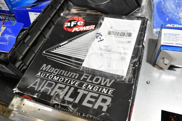 Lot includes various items in black poly bin: aFe Power Magnum FLOW air filter box, license plate frame, assorted car parts.