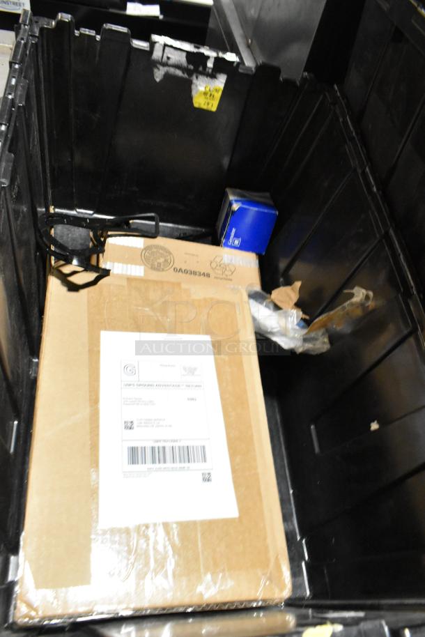 Lot of items in black poly bin, including an air filter and black license plate frame. Boxes with labels visible.