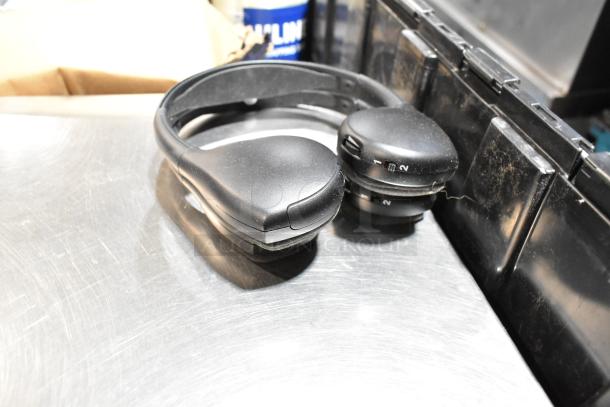 Lot including black headphones and tape in a black poly bin. Headphones show minor wear, multi-channel selector visible.