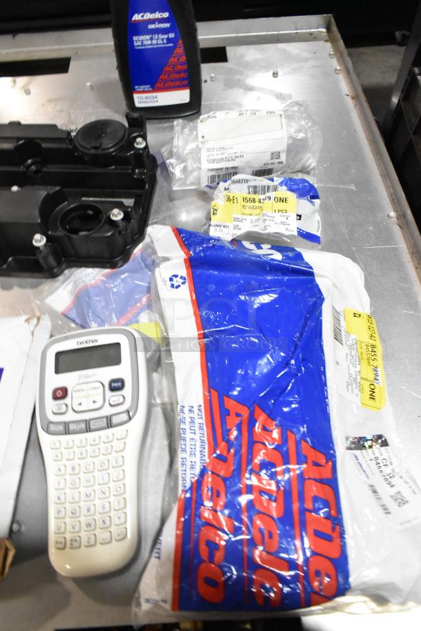 Lot of items in black poly bin; includes ACDelco Dexron LS gear oil and Brother label printer. Various packaging visible.