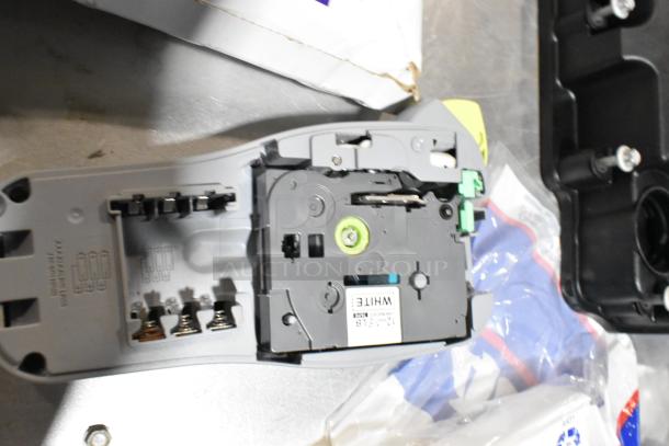 Lot includes Brother label printer with battery slots and attached white label tape, open with visible internal components.