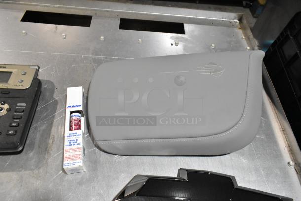 Lot of various items including a corded telephone, ACDelco lacquer touch-up paint, and a gray padded item on metal surface.