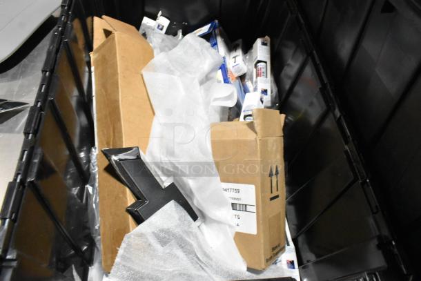 Lot of miscellaneous items in a black poly bin, including a corded telephone and thermometer, visible packaging and boxes.