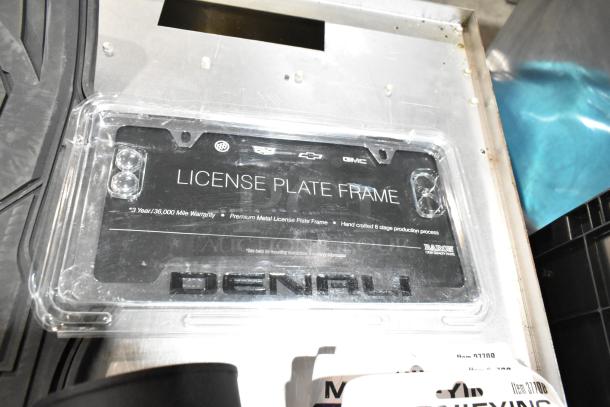 Lot of various items including black floor mats and headphones in poly bin; license plate frame with logos and warranty info visible.